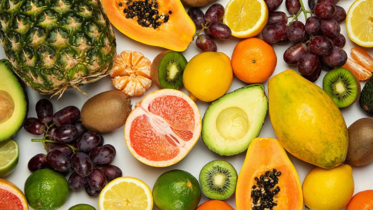 An assortment of fruit including kiwis, grapes, citrus fruit, a pineapple, etc.