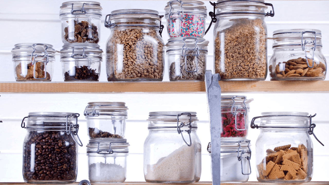 Two shelves filled with glass jars of various nuts, seeds, crackers, and baking ingredients.